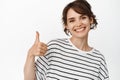 Close up of smiling young woman show thumbs up, like and approve, recommend smth good, excellent choice, standing over