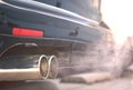 Close up of smoky dual exhaust pipes from a starting diesel car.