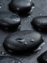 Close up of smooth black river stones on a reflective surface with soft lighting and deep contrast in a minimalist Royalty Free Stock Photo