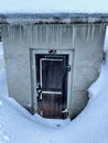Close up of snow covered little concrete shed with icicles hanging from roof.