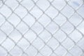 Close up of snow laying on the squares of a wire farm fence with snow in background - Image