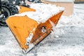 Close-up snowplow of big tractor machine removing and cleaning snow after storm on icy road or city street at alpine mountain