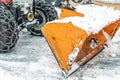 Close-up snowplow of big tractor machine removing and cleaning snow after storm on icy road or city street at alpine mountain Royalty Free Stock Photo