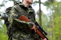 Close up of soldier or hunter with gun in forest