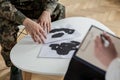 Close-up of soldier`s hands touching papers with ink stains during a therapy