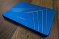 Close-up: A solid-state drive in a blue metal case lies on a surface with a wooden texture Royalty Free Stock Photo