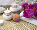 Close up spa composition with bath bomb, tulips, candles and pebbles on wooden background