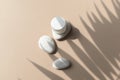 Close up spa massage composition with cosmetic cream glass and pebbles on beige background.