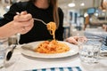 Close-up spaghetti Bolognese wind it around a fork. Parmesan cheese. Young woman eats Italian pasta with tomato, meat. Royalty Free Stock Photo