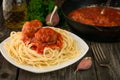 Close-up of spaghetti with meatballs and a pan with meatballs in tomato sauce with garlic and onions on a rustic table Royalty Free Stock Photo