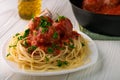 Close-up of spaghetti with meatballs with tomato sauce and parsley in white plate and black pan with meatballs Royalty Free Stock Photo