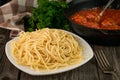 Close up spaghetti in a plate and a pan with meatballs in tomato sauce on a rustic wooden background Royalty Free Stock Photo