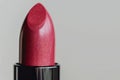 Close-up of a sparkling red vegan lipstick on a light background, perfect for beauty and cosmetics