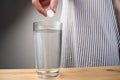 Close up sparkling water glass with dissolving effervescent aspirin pill standing on wooden table