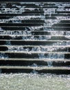 Close-up of sparkling water spashing down concrete stairs in a fountain into pool below  with water drops in the air Royalty Free Stock Photo