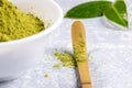 Close-up special wooden bamboo spoon with green matcha tea powder, white bowl with tea powder and fresh leaves on grey Royalty Free Stock Photo