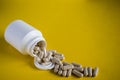 Close up of spilled medical pills from pill bottle on yellow background Royalty Free Stock Photo