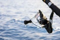 Close up spinning fishing rod against blue sea watger background