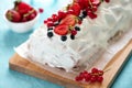 Close-up sponge biscuit cake roll filling whipped cream and berries decorated strawberry, blueberry and red currants on turquoise