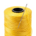 Close-up of a spool of bright yellow thread with a sewing needle threaded through it on a white background Royalty Free Stock Photo