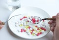 Close-up, Spoon full of colorful pills in hand woman and pills in a plate. Royalty Free Stock Photo