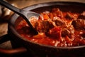 Close-up of a spoon scooping up spicy goulash with chunks of tender beef and paprika, served in a rustic ceramic bowl