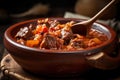 Close-up of a spoon scooping up spicy goulash with chunks of tender beef and paprika, served in a rustic ceramic bowl