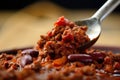Close-up of a spoonful of chili con carne with vibrant red color and texture of ground beef, beans, and tomatoes