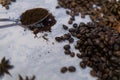 Spoonful of coffee surrounded by piles of coffee beans on white surface