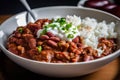 Close-up of a spoonful of red beans and rice topped with a dollop of sour cream and diced tomatoes