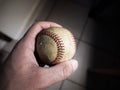 Close up sports background image of a male hand holding an old used weathered leather baseball between his thumb and fore finger Royalty Free Stock Photo