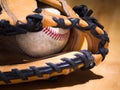Close up sports background image of an old used weathered leather baseball with red laces inside of a baseball glove or mitt Royalty Free Stock Photo