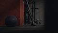 Close-up of sports equipment in gym. Black fitness ball and rod neck on background of kettlebells and dark walls of
