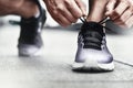 Close-up of sportsman tying sneakers. Unrecognizable man stopping lacing shoe outdoors. Athletic shoes concept. Color Version Royalty Free Stock Photo