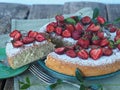 Spring berry cake with strawberries at the top on a wooden background