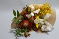 Close-up spring bouquet of ruscus, leucadendron, leucospermum, iris, cotton, mimosa branch, tulip on a gray background