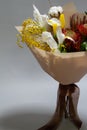 Close-up spring bouquet of ruscus, leucadendron, leucospermum, iris, cotton, mimosa branch, tulip on a gray background, selective