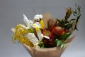 Close-up spring bouquet of ruscus, leucadendron, leucospermum, iris, cotton, mimosa branch, tulip on a gray background, selective