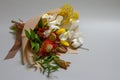 Close-up spring bouquet of ruscus, leucadendron, leucospermum, iris, cotton, mimosa branch, tulip on a gray background, selective