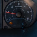 Close up square view of the bright orange engine trouble light illuminated on a dashboard dial in a vehicle Royalty Free Stock Photo