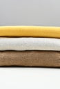 Close up of stack of beige, brown, mustard knitted pullovers, side view. Simple minimal cozy clothes concept