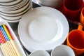 Close up stack of blank clean white dishes, bowls, plates, mugs and colorful wooden chopsticks on metal tray, copy space Royalty Free Stock Photo