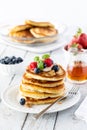 Close up of a stack of buttermilk pancakes, topped with fresh berries and banana slices and served with maple syrup. Royalty Free Stock Photo