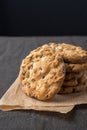 Close-up of a stack of chocolate chip cookies on brown paper and dark tablecloth, black background Royalty Free Stock Photo