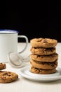 Close-up of stack of chocolate cookies in white plate and white cup, on white wooden table, black background, Royalty Free Stock Photo