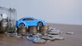 Close up stack of coin, glass bottle and toy car on table.saving and manage money to success transport business