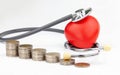 Close up stack of coins, red heart and stethoscope on white background. Royalty Free Stock Photo