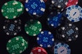 Close up stack of different colored poker chips of diverse value isolated on the black casino table background