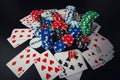 Close up stack of different colored poker chips, playing cards and dices isolated over black casino table background. Gambling