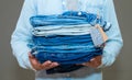 close up stack of folded blue jeans in hand over gray wall background, copy space. Royalty Free Stock Photo